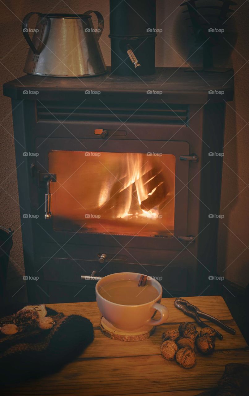 A hot drink and snacks in front of an old iron wood burning stove.