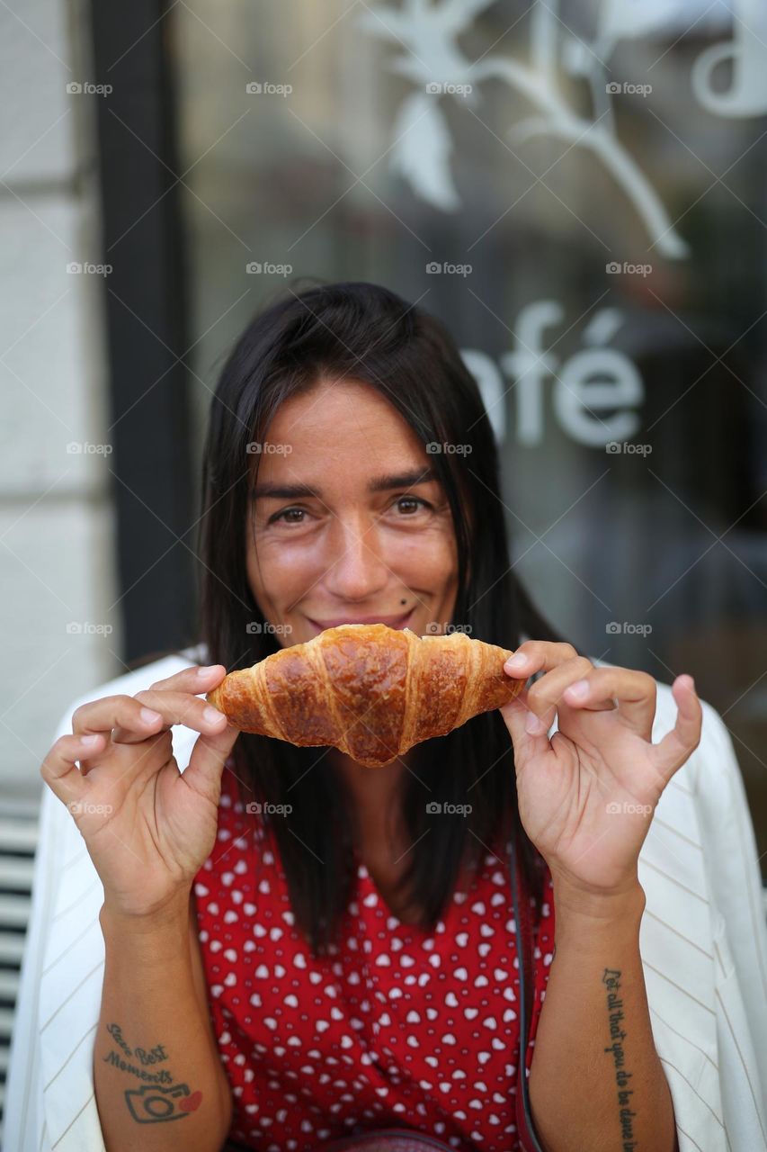 Salut France, beautiful girl eat croissant at the street cafe 