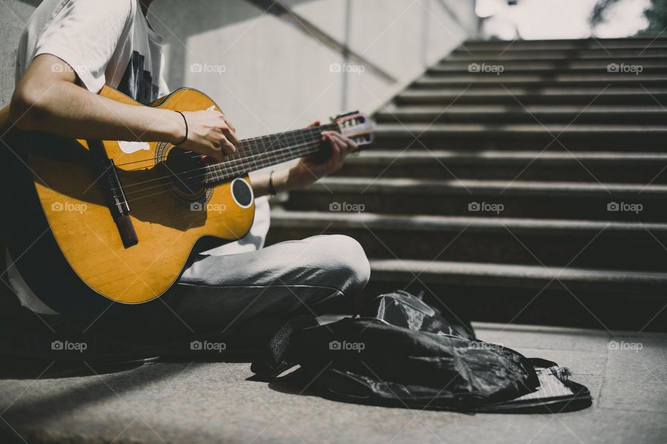 Street performer plays guitar .  Young street musician playing guitar and busking for money.