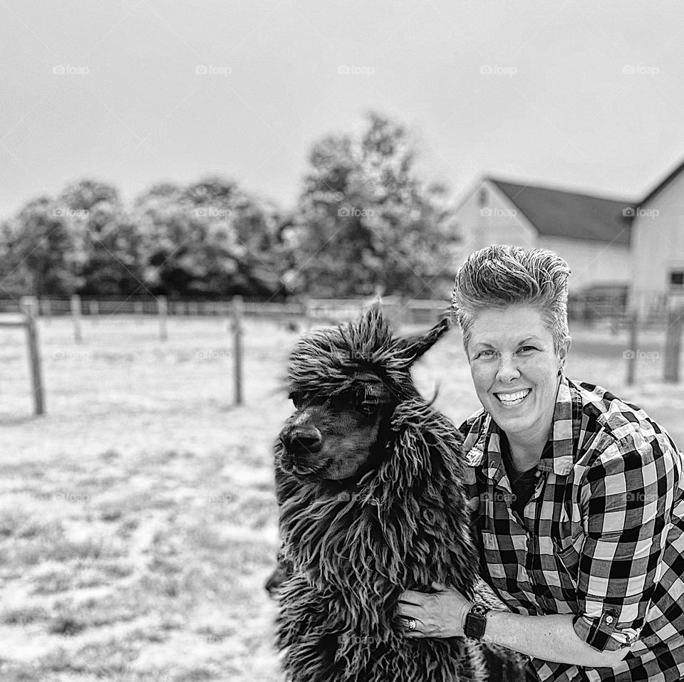 Woman poses with an alpaca on a farm, fun with alpacas on the farm, alpacas bring joy to humans, loving alpacas calms the soul, moments of happiness 