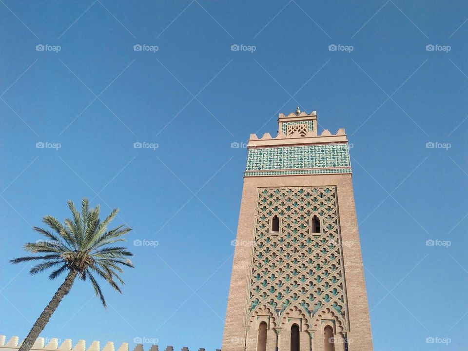 The palm tree and a magic minaret of a mosque at marrakech city in Morocco.