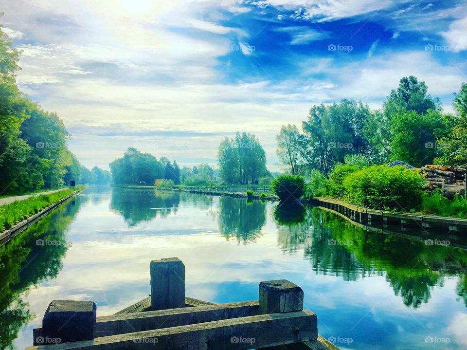 A sunny sky reflected in the water of a river 