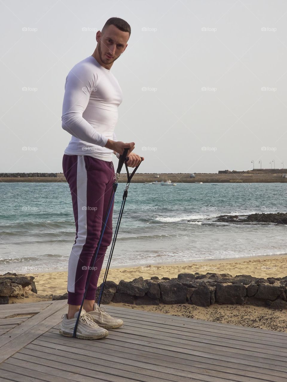 modelo realizando ejercicio con bandas elásticas en la calle con vistas al mar