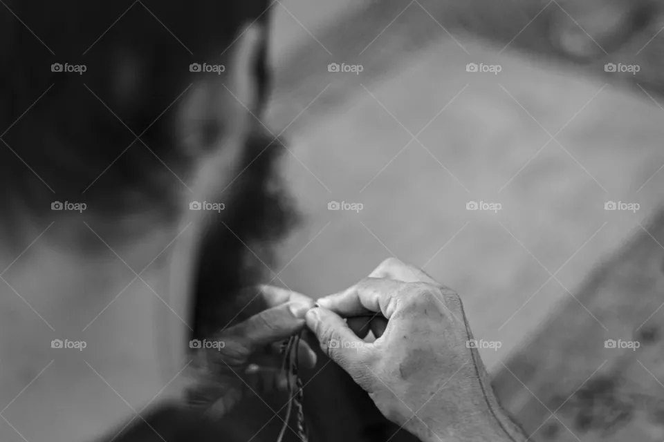 A foto mostra um jovem realizando trabalho artesanal em sua oficina.