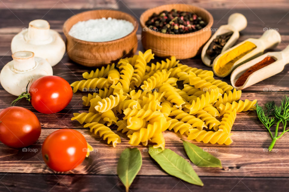 Raw pasta with ingredients and wooden accessories