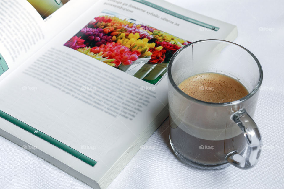 A cup of coffee and a photographic book on a white background