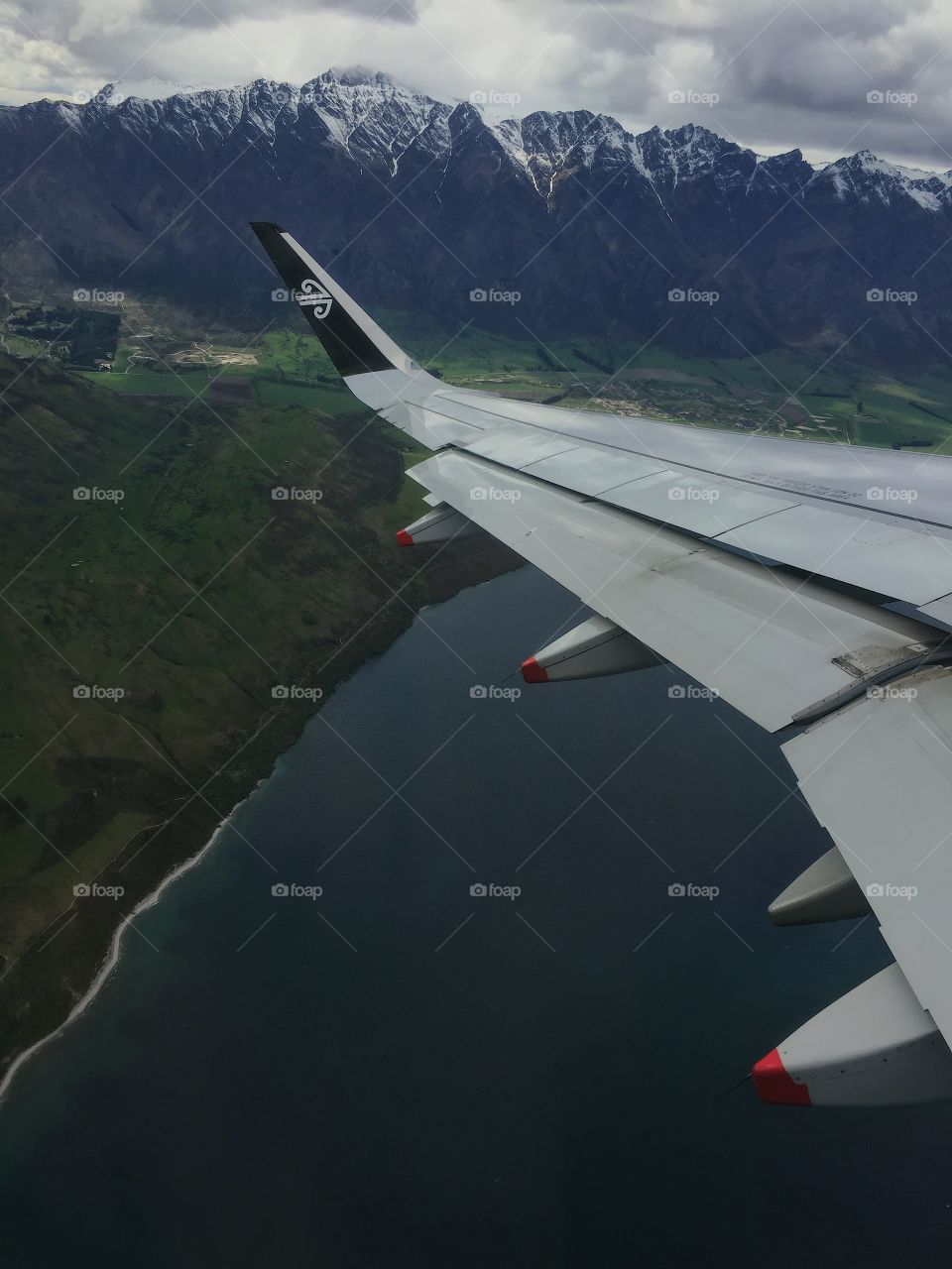 Aircraft wing flying over lake and mountains 