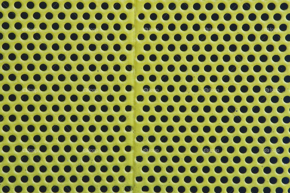 A closeup abstract of a green perforated metal trash container.