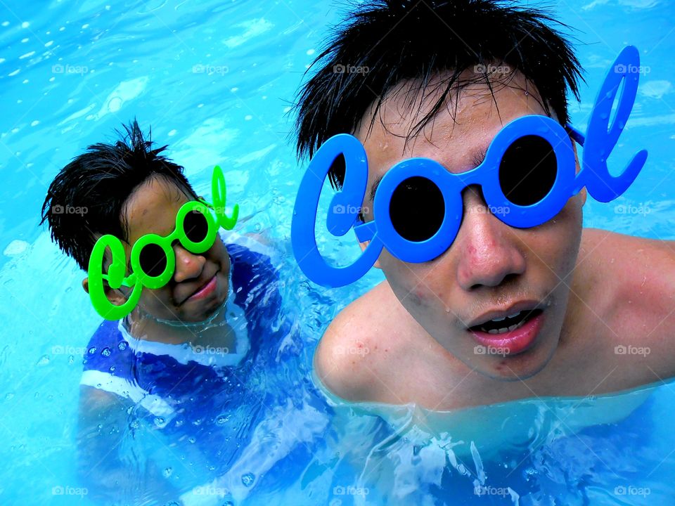 young boys in a swimming pool wearing funny sunglasses