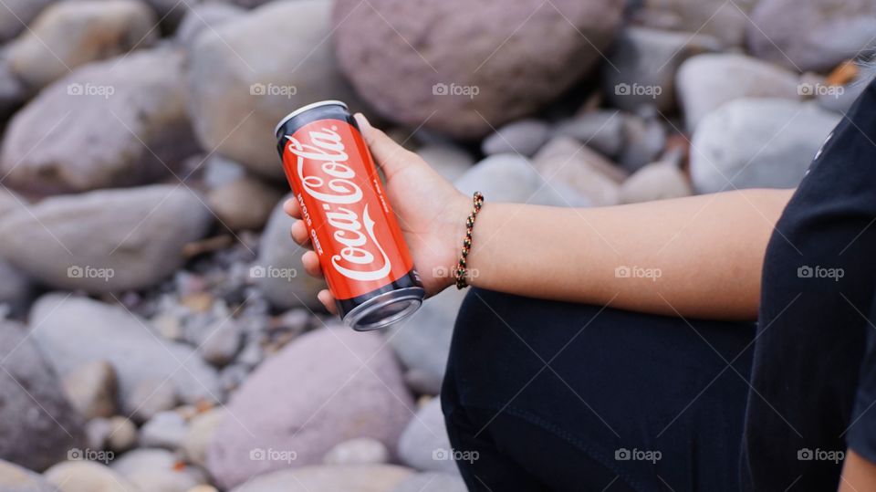 Close up the hand of a woman who is holding a can of coca cola