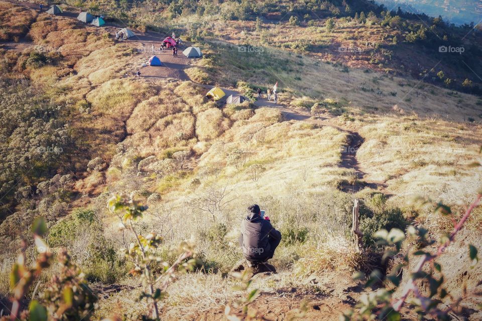 Back packer use his smarts phone on the mountain at Indonesia 