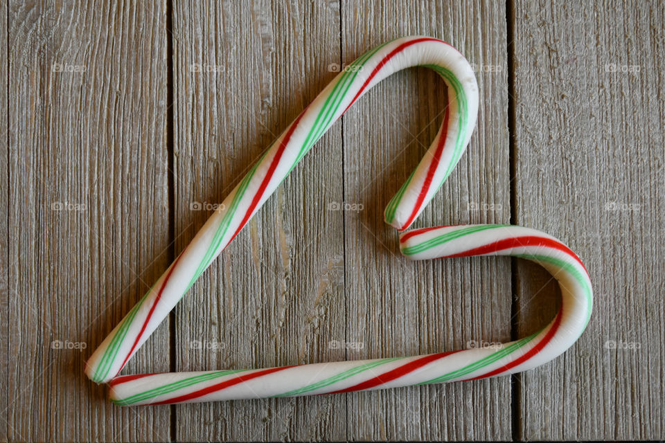 Candy canes in the shape of a heart on wood background