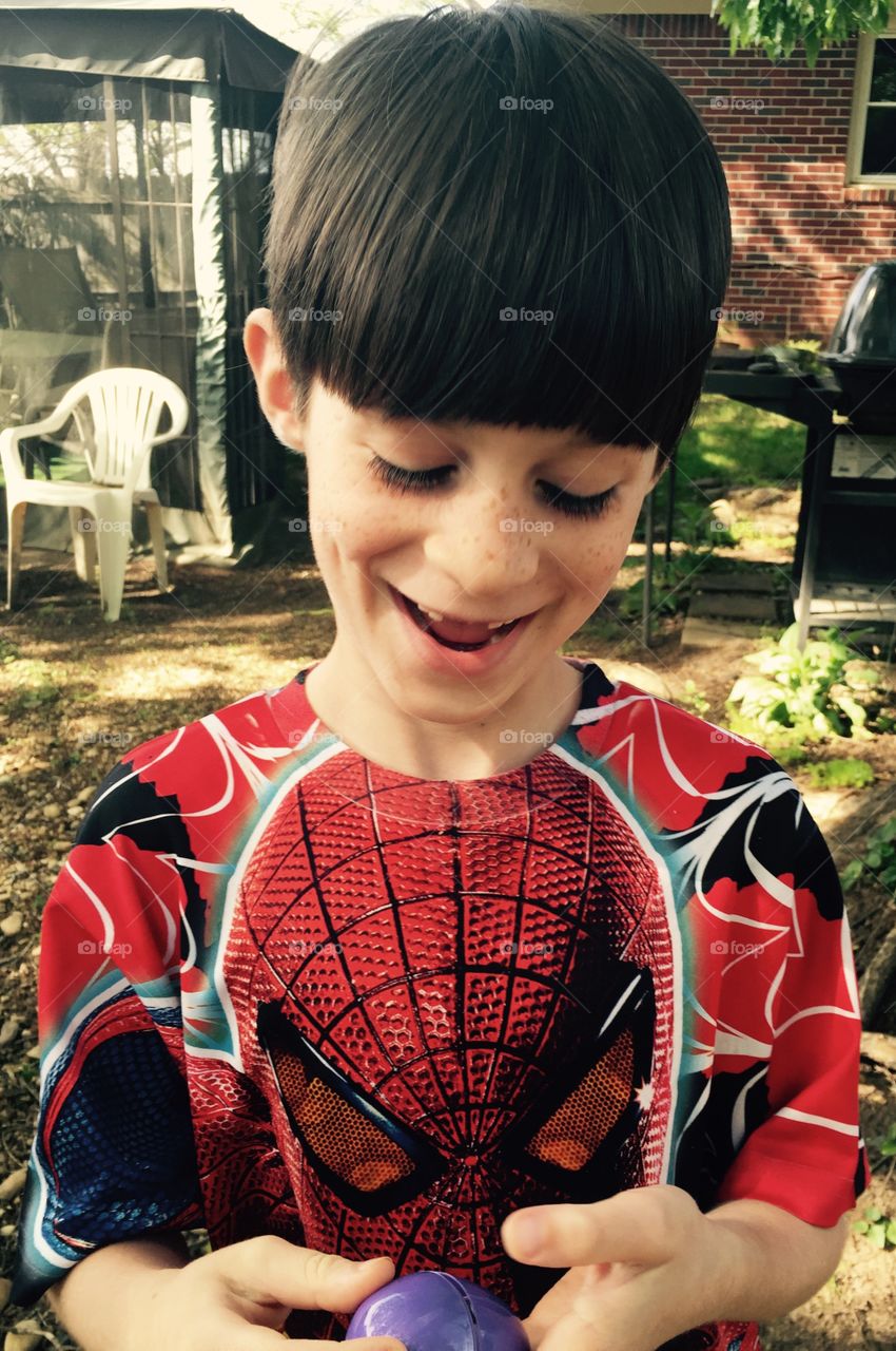 Young boy looking at his purple egg he found on his egg hunt.