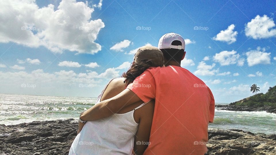 Young couple together sitting rocky beach