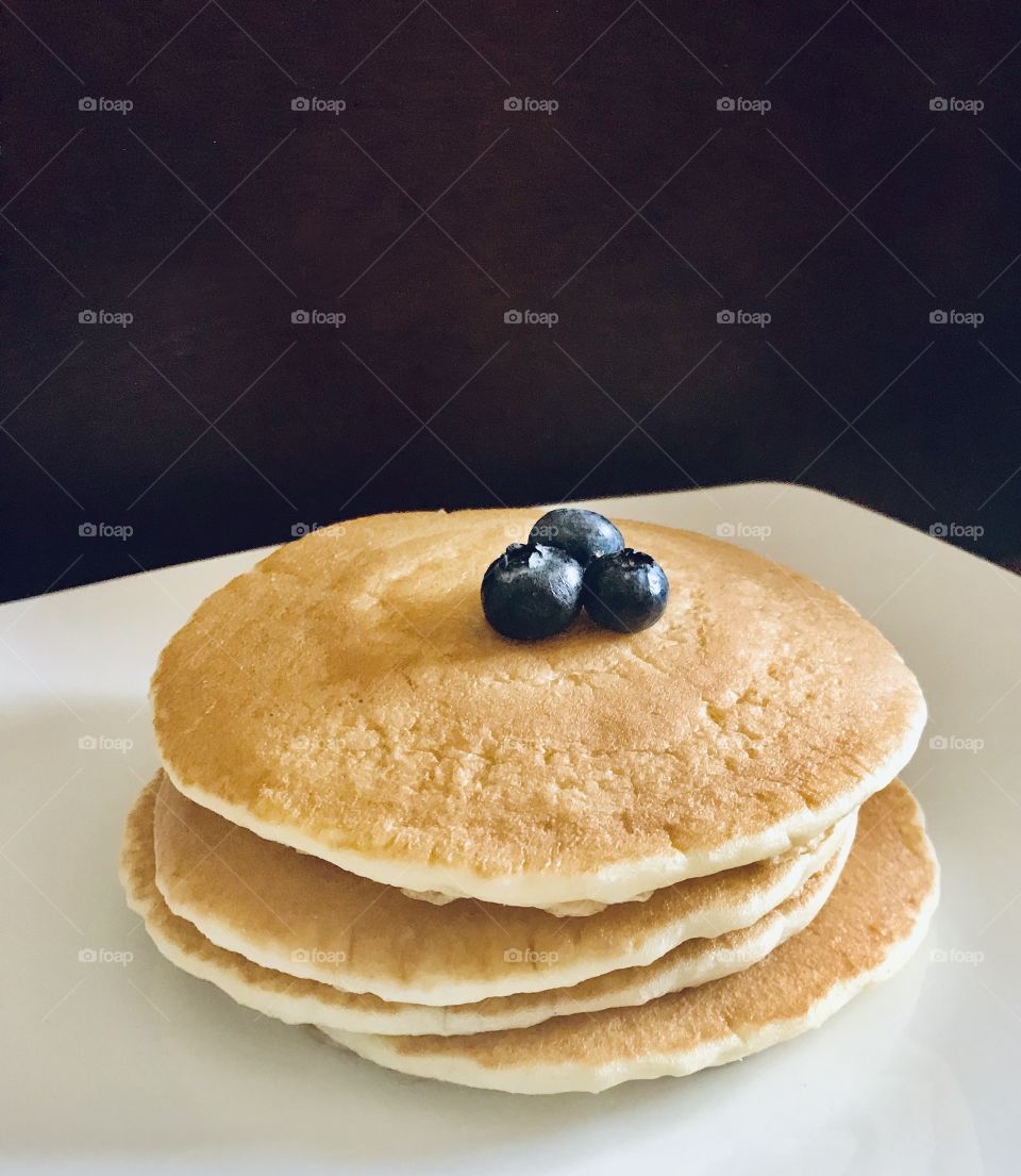 A stack of delicious golden pancakes stacked with blueberries 