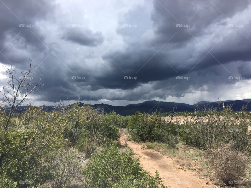 A storm threatens on the homeward stretch along a trail in the desert. Rain will arrive soon.