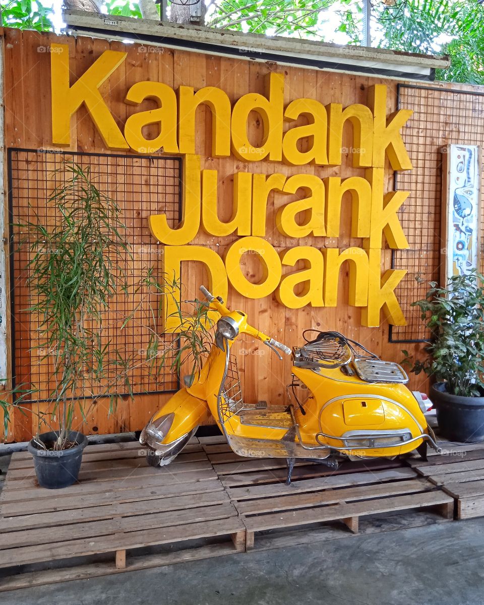 A yellow vespa displayed on a stage