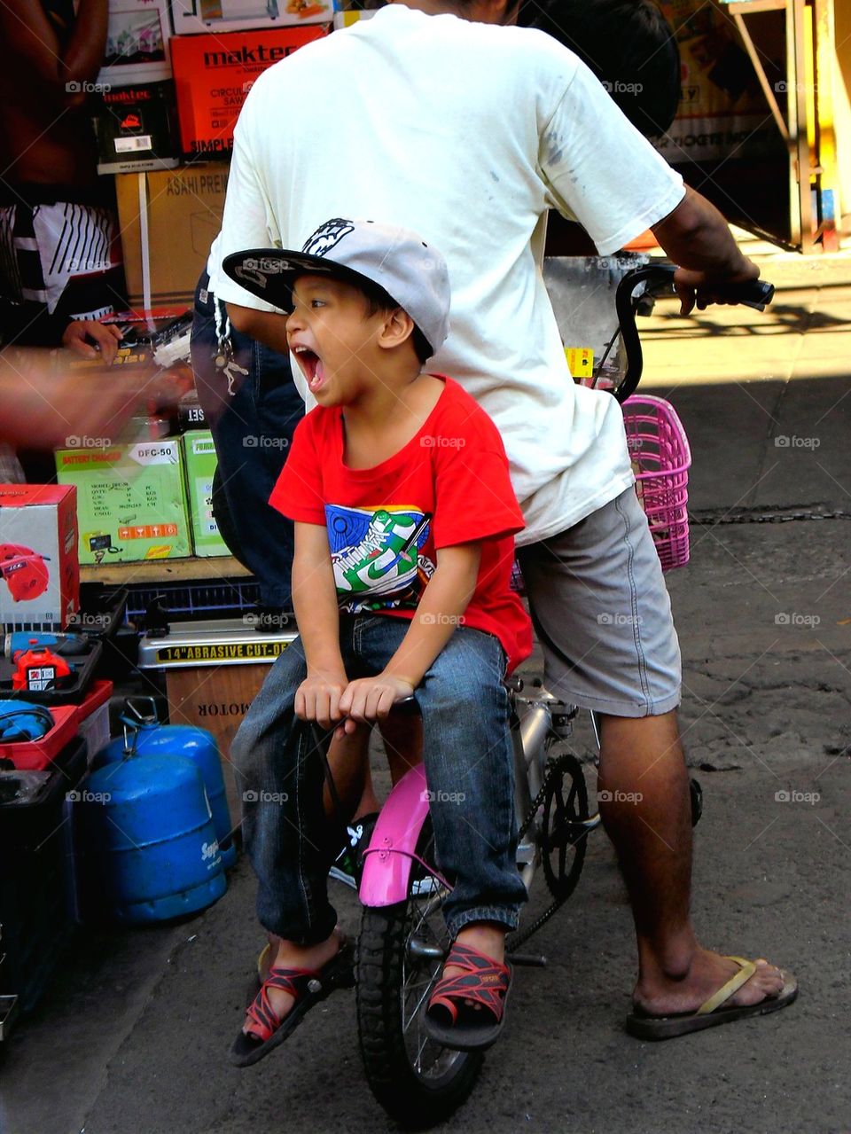little asian kid riding at the back of a bicycle