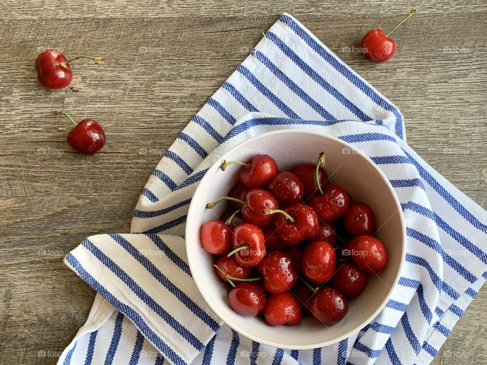 Cherries in a bowl on striped dish towel 