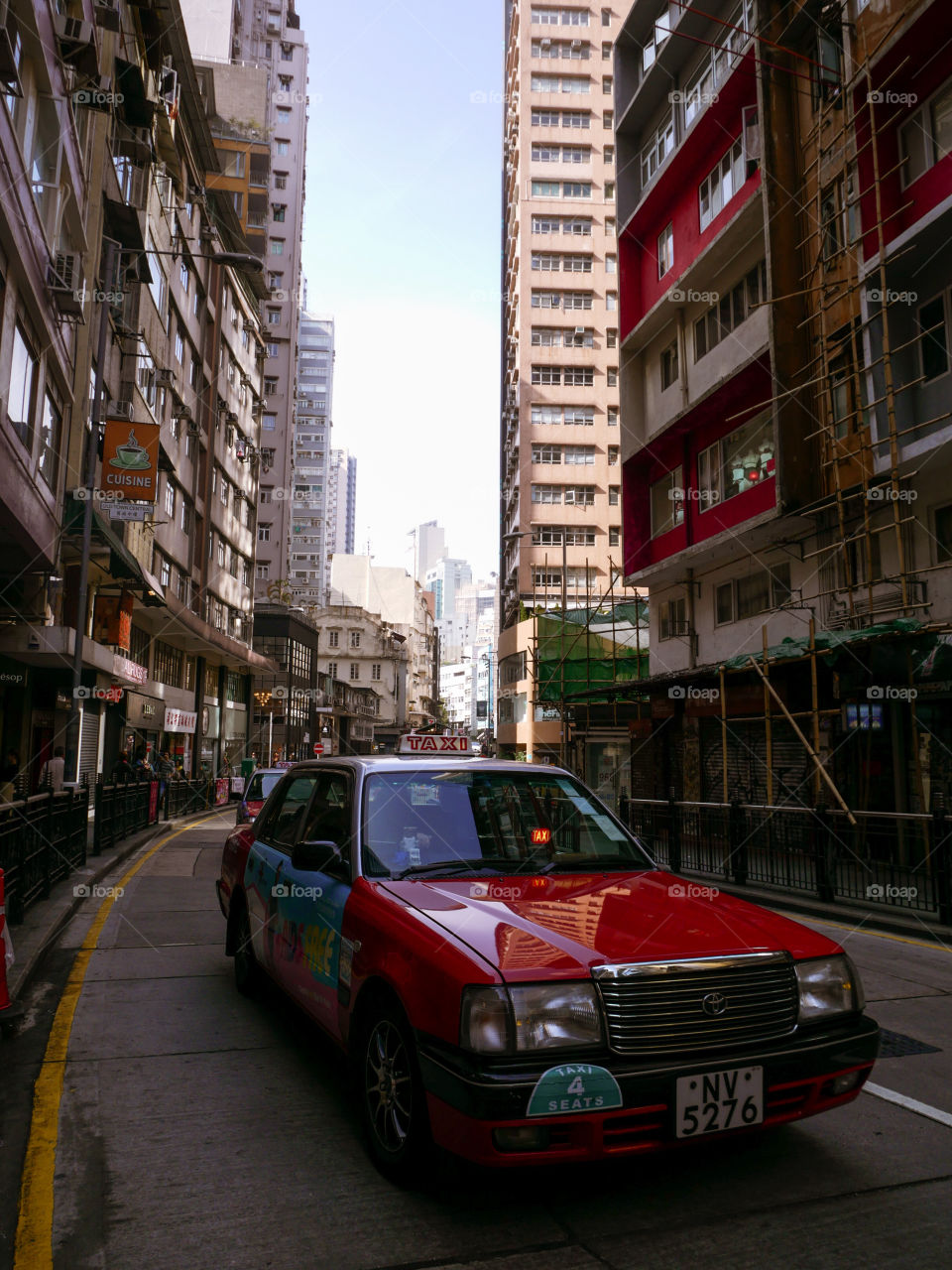 A shot of a red taxi in Hong Kong streets. A vintage feel to the photo on a bright winter day