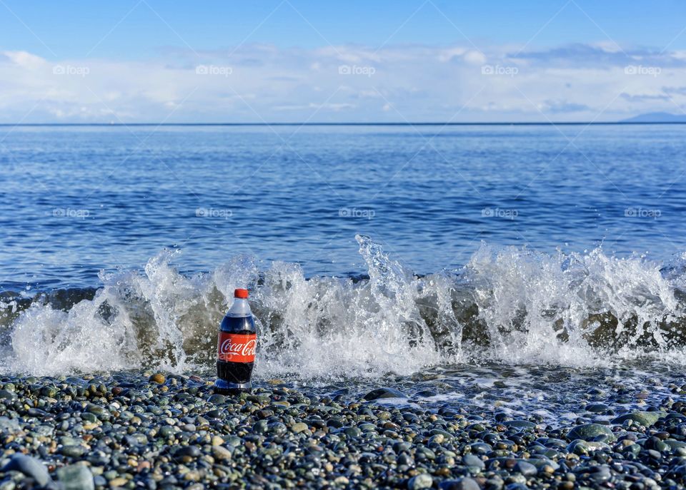 Cola bottle on beach as waves splash 