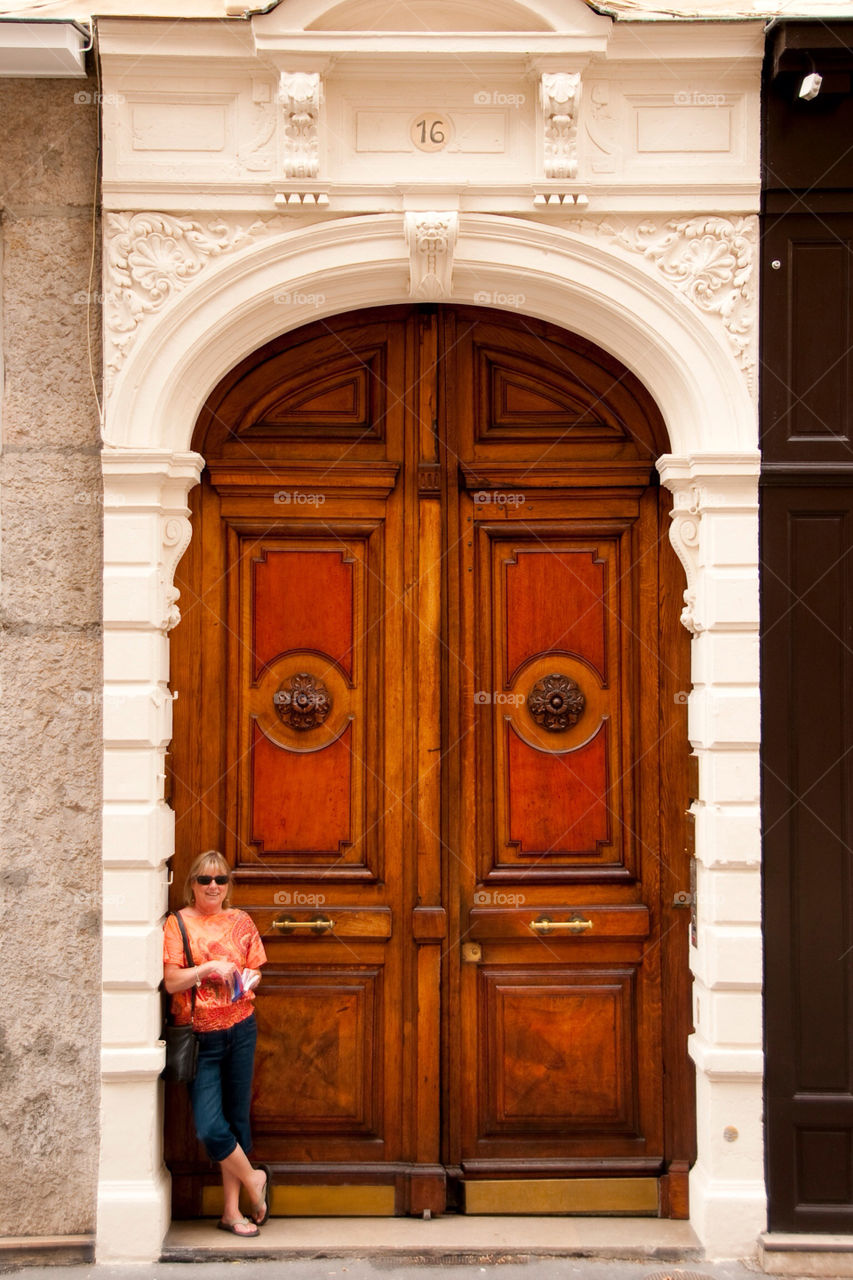 Woman leaning on an entryway with a wood door