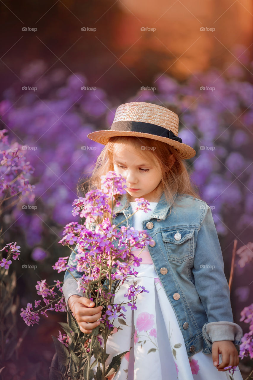 Cute little girl portrait in blossom meadow at sunset 