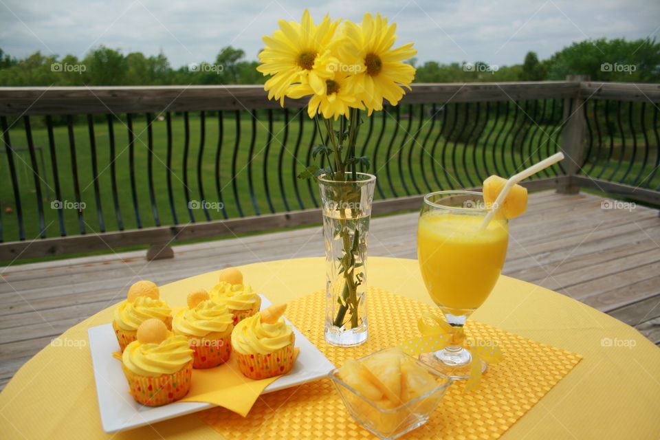 Sunny Days. Yellow cupcakes with homemade buttercream icing, pineapples, smoothie and daisies make a sunshine table setting. 
