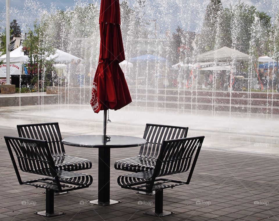 A nice outdoor table with an umbrella by the fountain at Centennial Park in Redmond in Central Oregon on a summer afternoon. 
