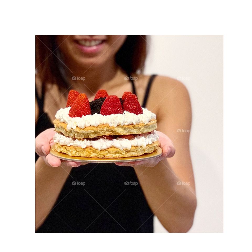Lady holding on to 6 inch 2 layered Strawberry shortcake that looks fresh and delicious 