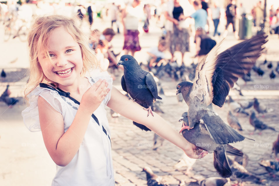 Smiling girl with pigeons on the arm