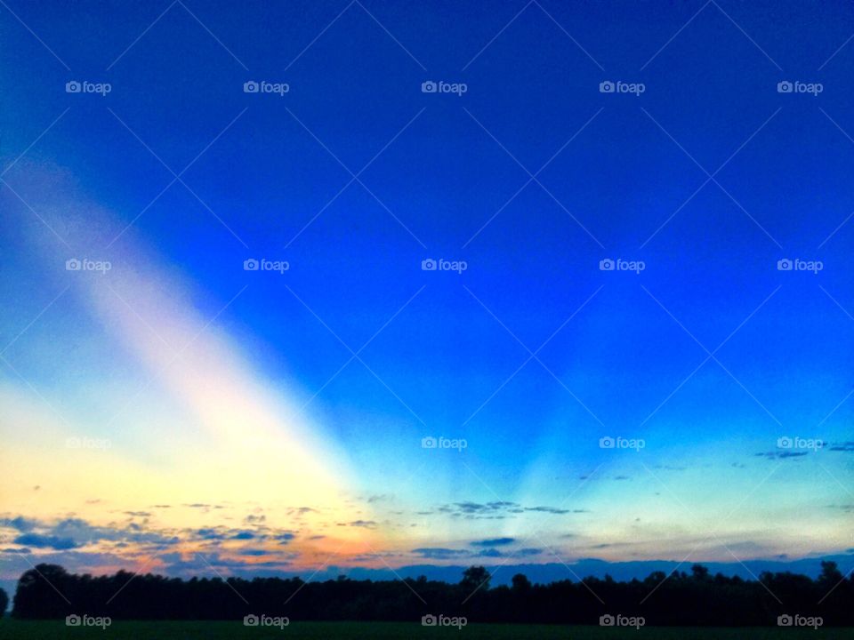 Rays of sun illuminate a deep blue sky