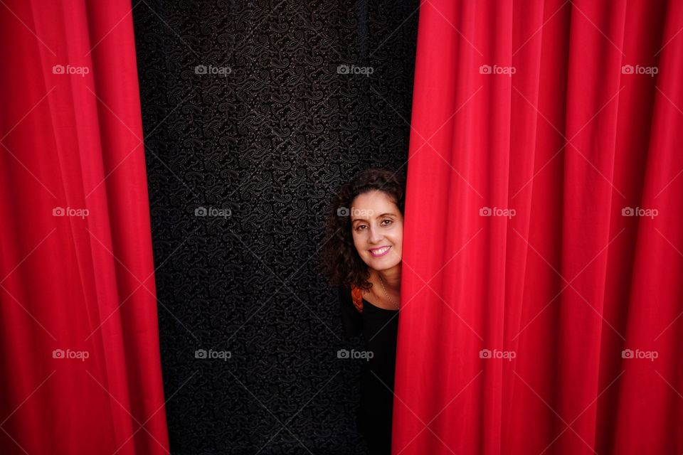 woman behind red theater curtain