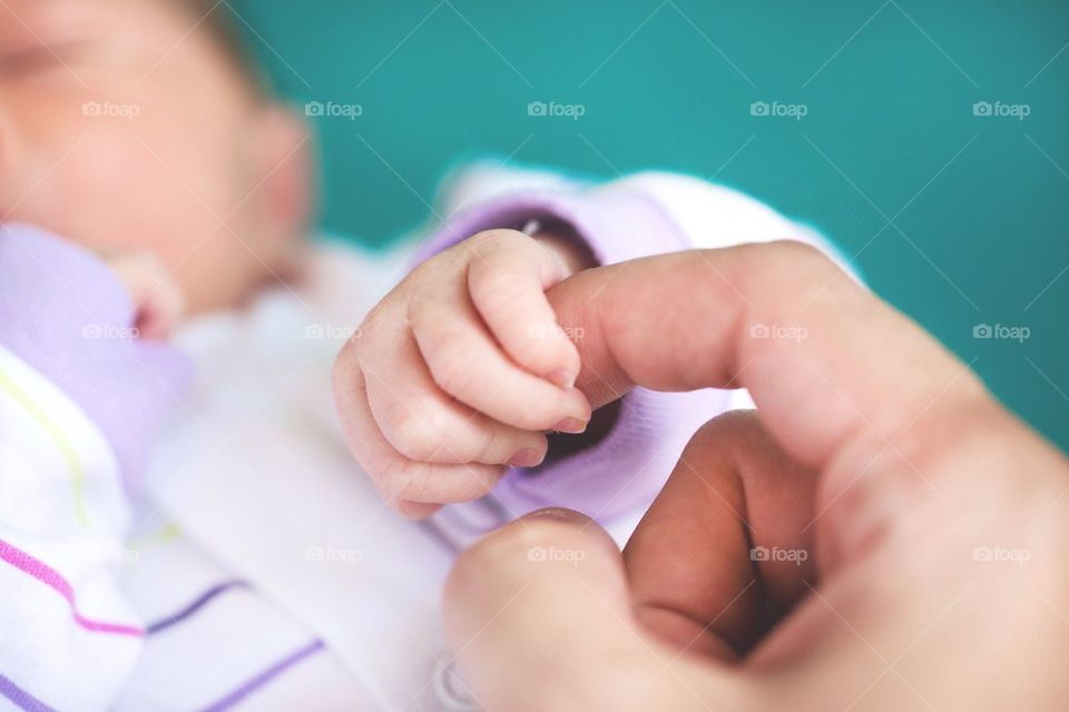 Close-up of baby girl holding father's finger