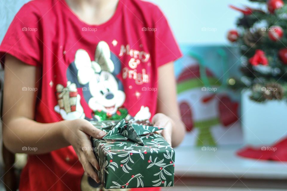 Girl in a bright Christmas t-shirt with a beautiful present in her hands