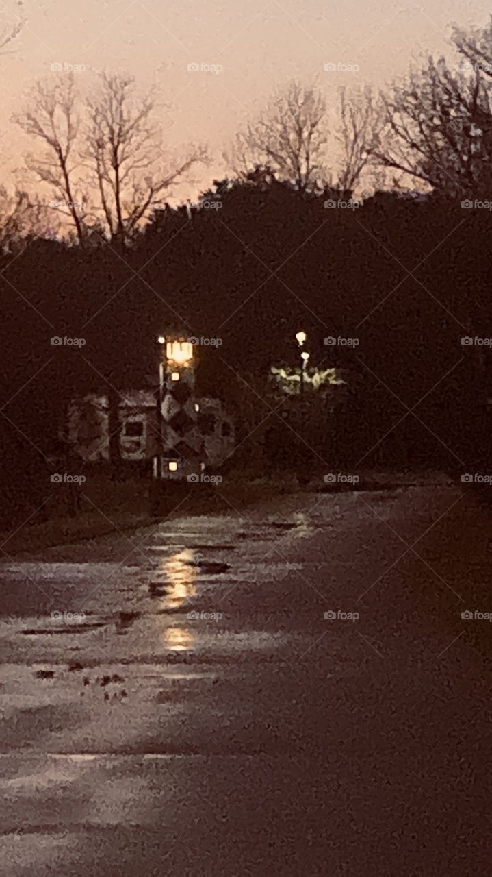 Night Shot of Lighthouse Reflections of Roadway from Previous Storms Wet Rainwater’s Foot Print. Drainage to Lake. 