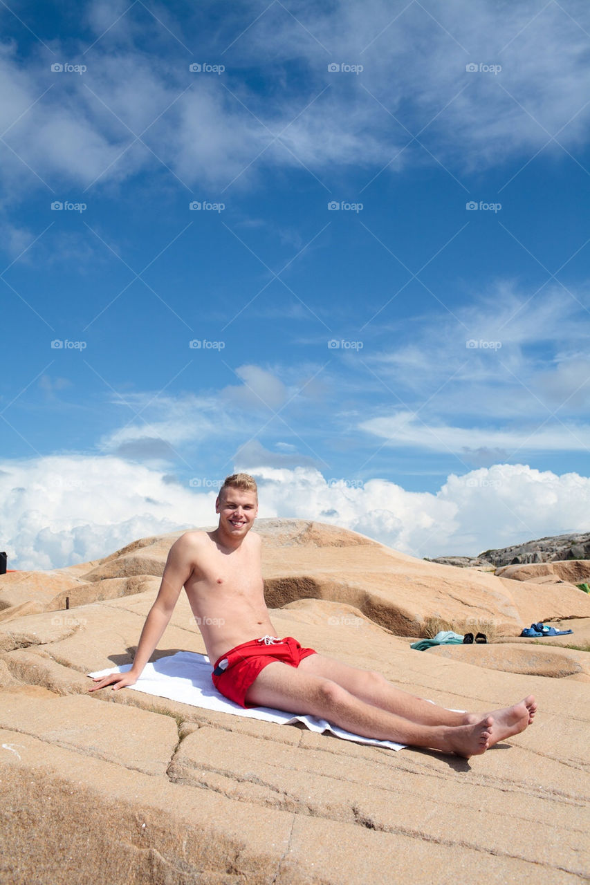 Happy man sunbathing on a cliff