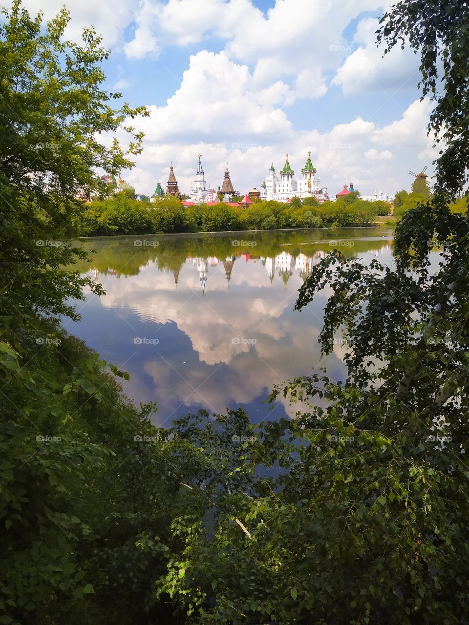 Summer landscape. Exit andforests to the river bank, on the opposite side of the dome of the towers. Reflection in water of trees, towers and sky with clouds
