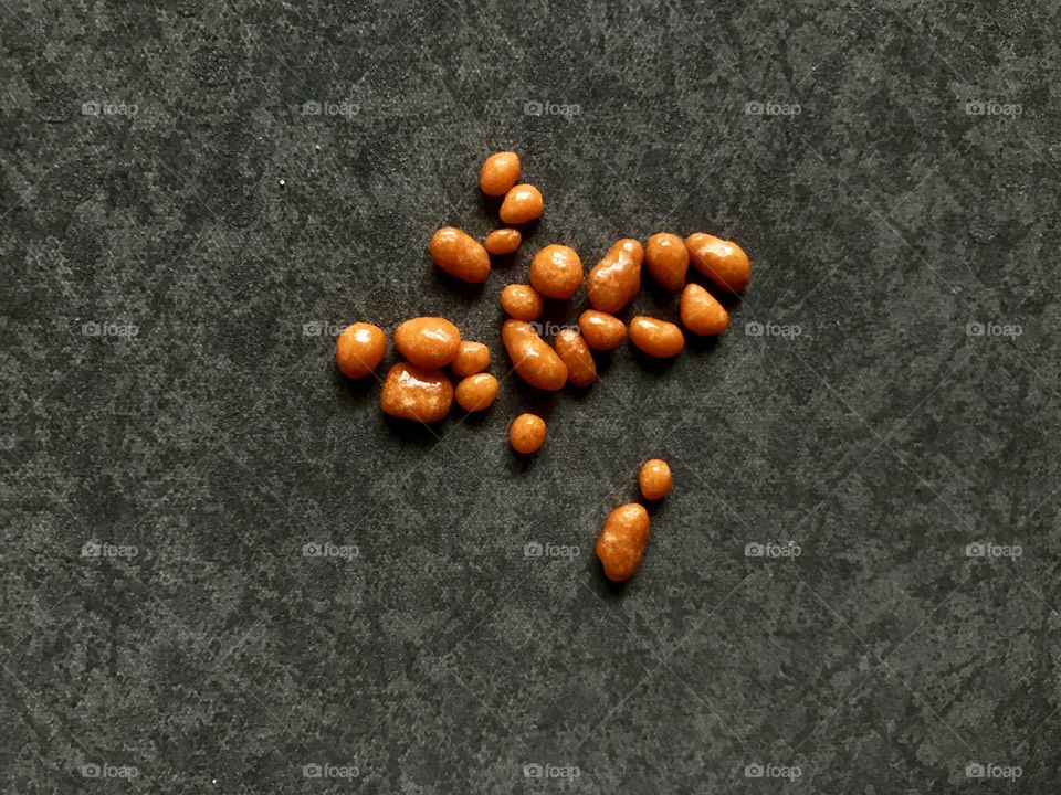 A lot of small orange sweets on grey background 