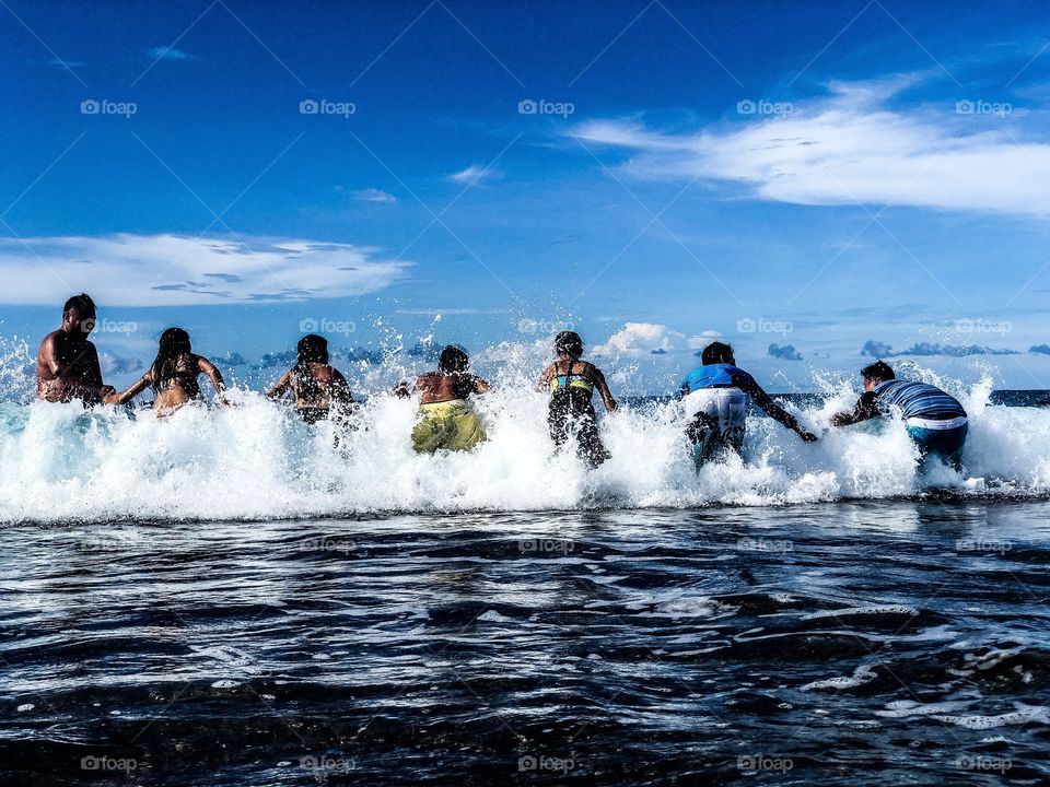 A group of young men holding hands agains the waves