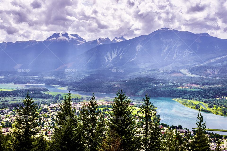 Light leaks through the clouds on the Selkirk mountain range in British Columbia, Canada. The town of Golden in the river valley