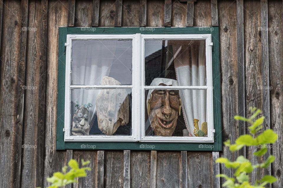 Wooden faces looking out through the window 
