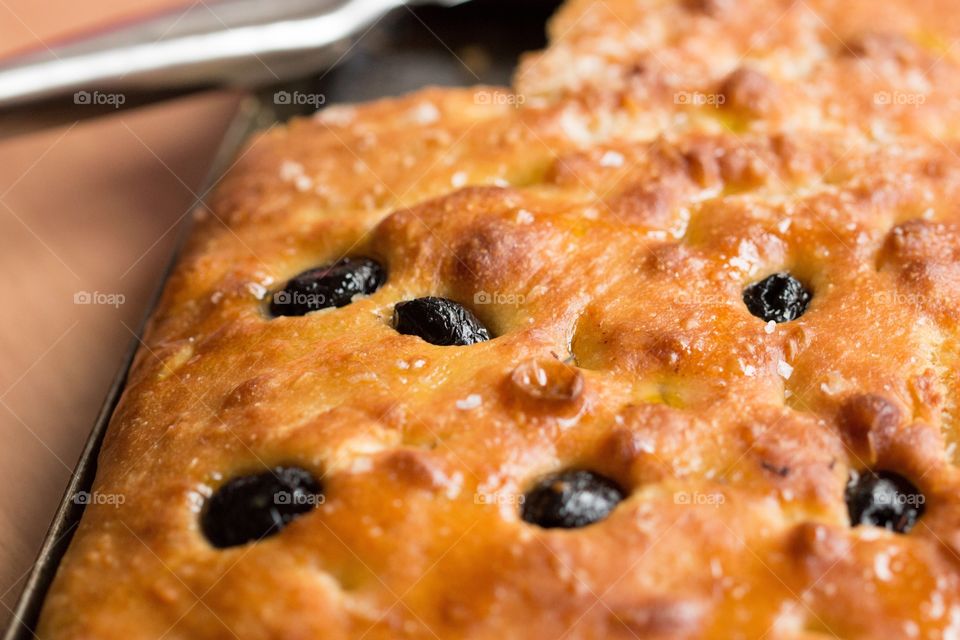 Olive focaccia bread. Italian focaccia bread with olives in close-up with a knife in background