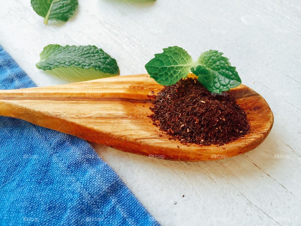 Black tea with mint leaf in wooden spoon