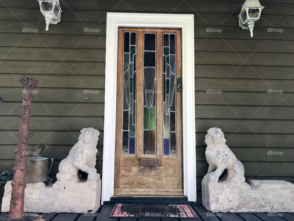 Wooden front door on a house with white lion statues on both sides