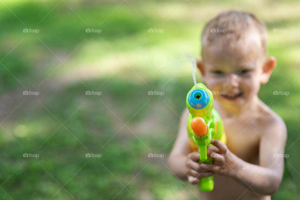 Kid playing with water gun toy in the summer