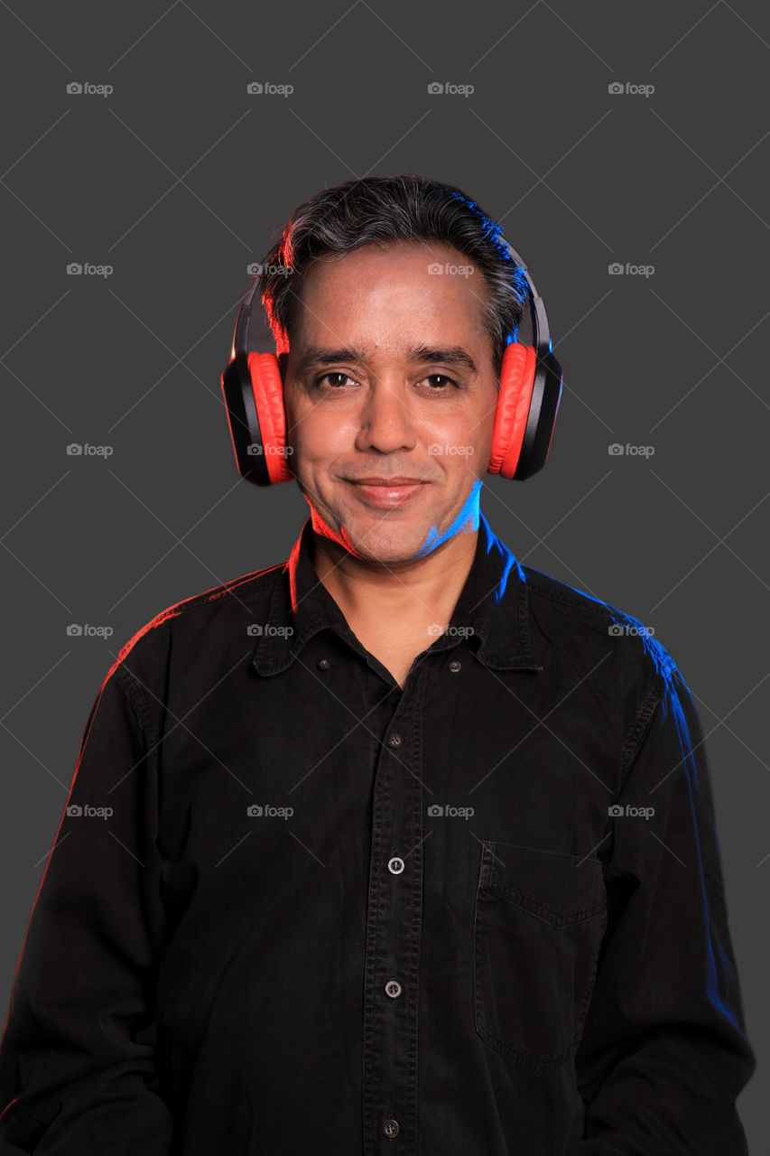 Indian man listening to music with wireless Bluetooth headphones