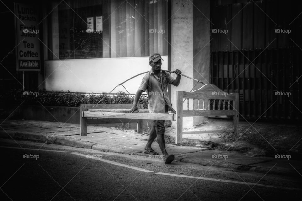 Man carrying bed frame on his shoulder