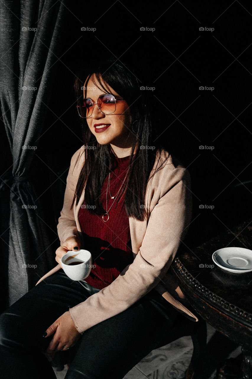 Beautiful brunette girl smile and take cup of coffee in street cafe