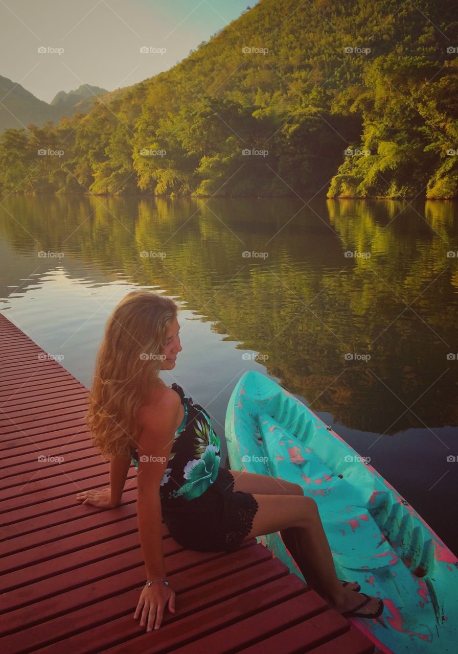 Woman sitting on pier on lake